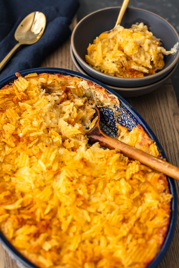cazuela de papas con queso en una cacerola azul junto a un tazón de papas con queso