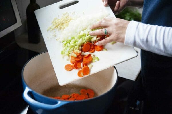 Coloque os legumes em uma panela para canja de galinha com macarrão caseiro.