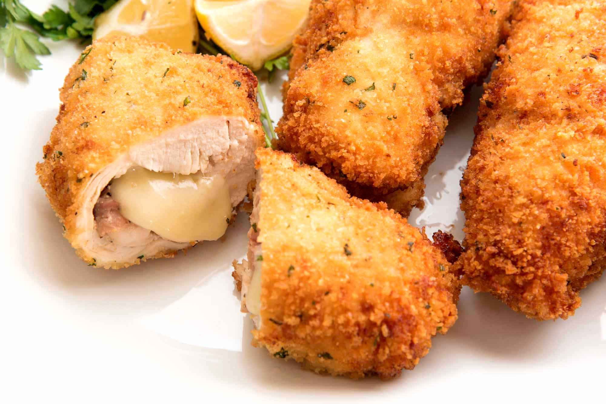 Frango caseiro Cordon Bleu em uma bandeja branca com fatias de limão.