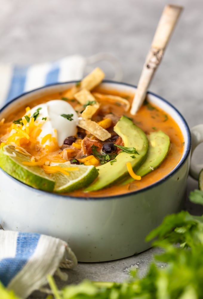 Uma tigela de sopa de tortilla com abacate, queijo e creme de leite