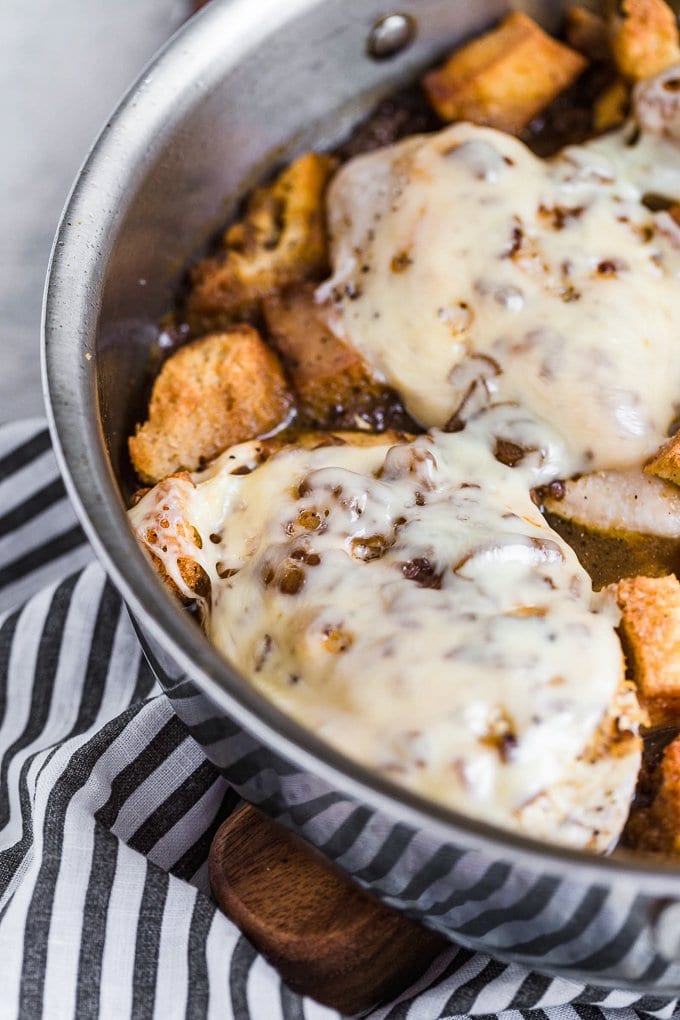 Pechuga de pollo cubierta de queso, con crutones en una sartén