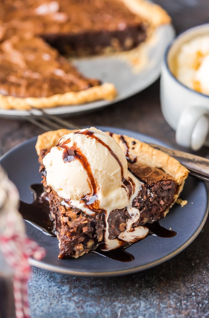 Brownie Pie es un rico postre de chocolate que es casi demasiado bueno para ser verdad. Una receta casera de brownie de chocolate horneado directamente en una masa de pastel te da dos postres en uno. Una rebanada de pastel de brownie con helado de vainilla y jarabe de chocolate