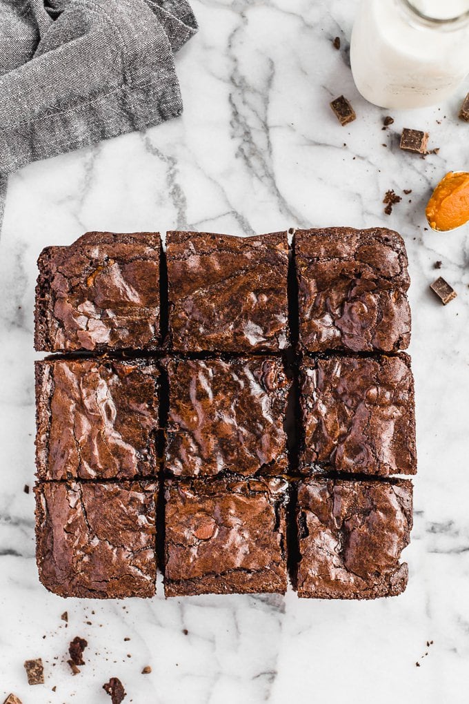 Brownies de abóbora são uma receita fácil de sobremesa de outono, perfeita para o Halloween ou o Dia de Ação de Graças. Adicione uma camada de abóbora aos seus brownies para algo divertido e delicioso! Brownies quadrados em uma mesa de mármore