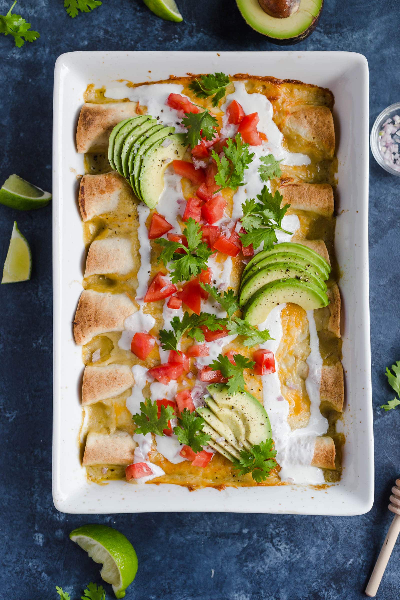 Un plato para hornear lleno de enchiladas de pollo fáciles hechas con queso, crema agria, salsa de enchiladas y más