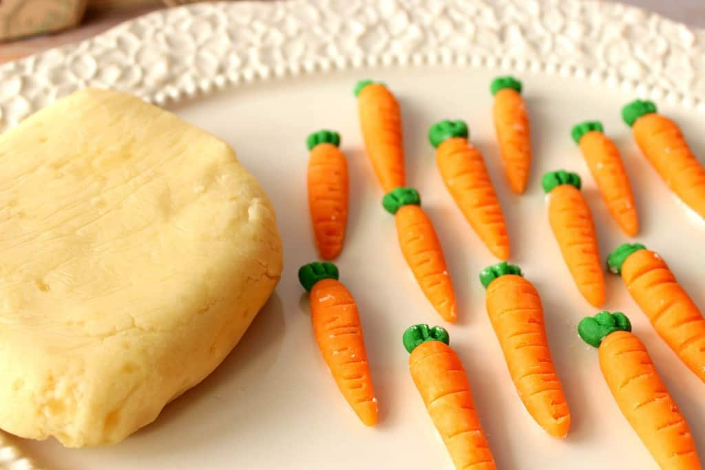 Bloco de doces caseiros de maçapão em um prato branco com cenouras caseiras de maçapão.