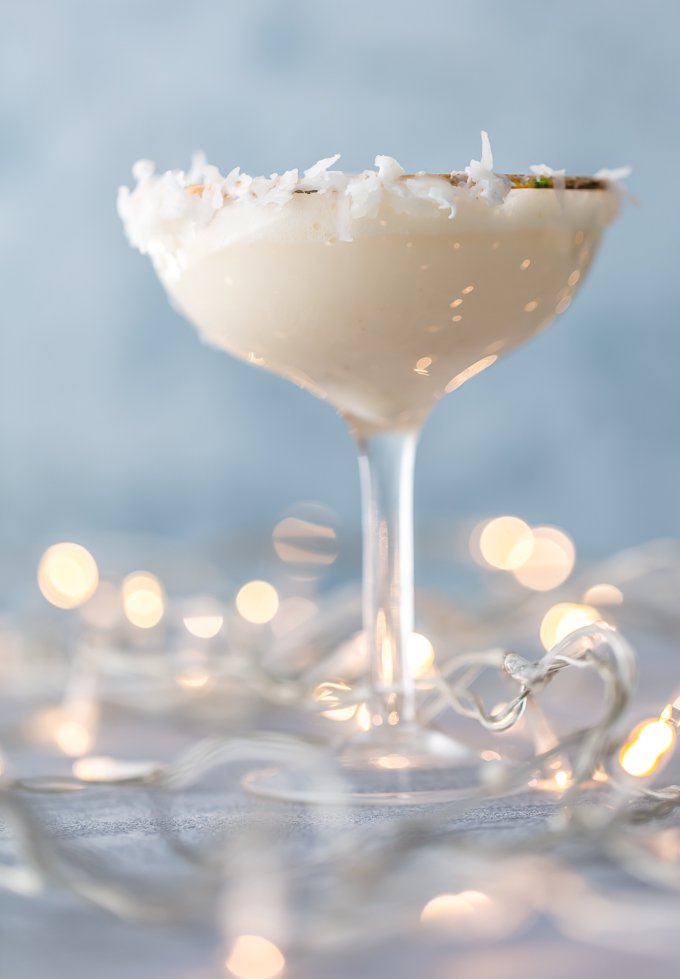 copa alta de martini llena de cóctel festivo. Borde de vidrio adornado con coco rallado