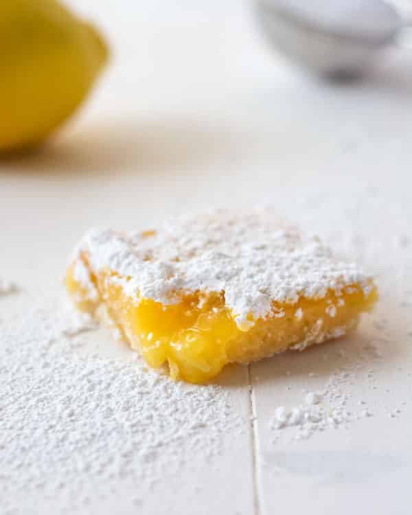 Quadrados de limão caseiros doces e azedos com uma crosta de manteiga. Crisp, base de biscoito leve coberto com recheio de limão ooey pegajoso!