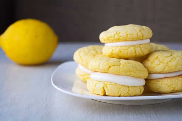 Biscoitos suaves e chewy de sanduíche de limão com cobertura de cream cheese picante! Eles começam com uma mistura de bolo e podem ficar prontos em 30 minutos!