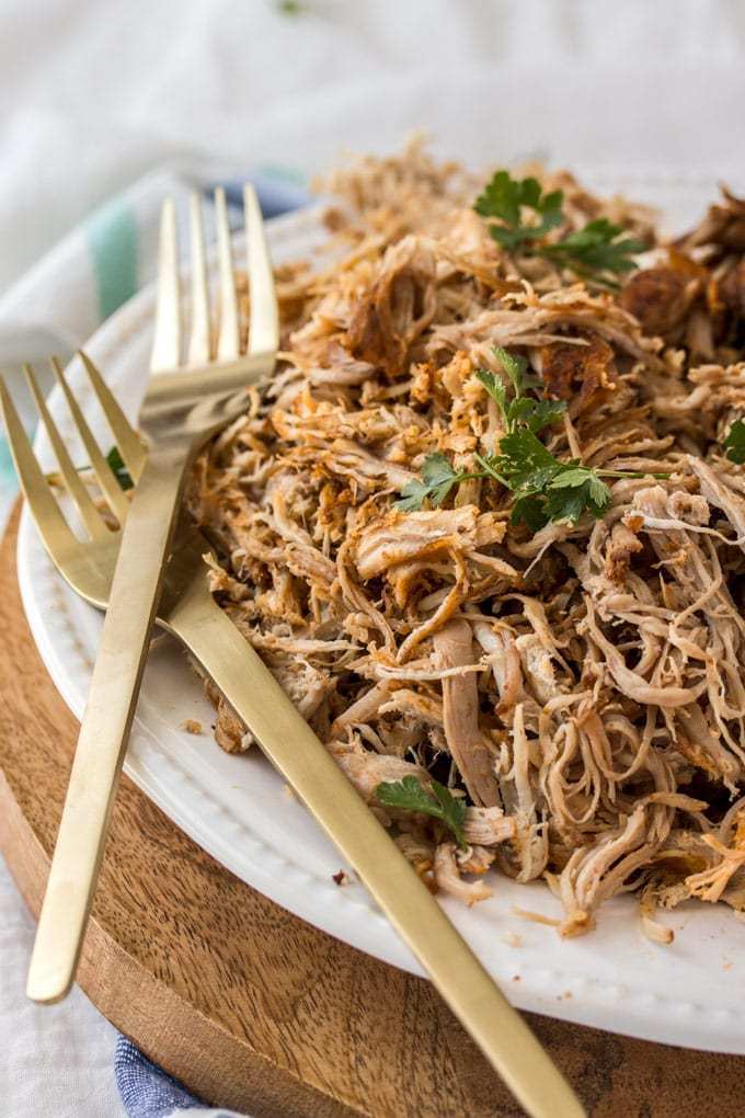 Un plato y dos tenedores con cerdo cocido recién desmenuzado