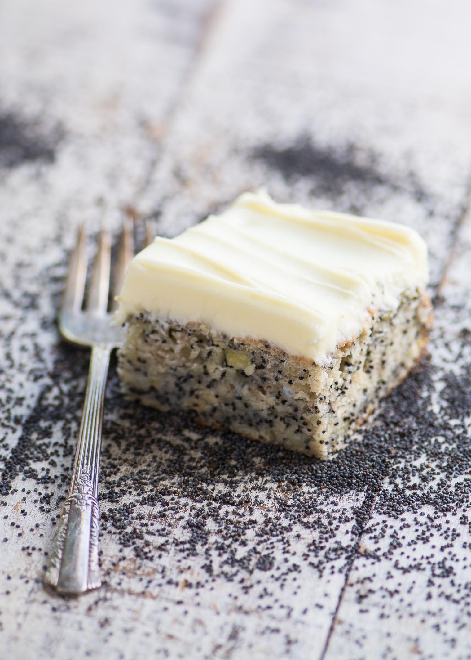 Um pedaço de bolo de sementes de papoila de banana com garfo em uma mesa de madeira