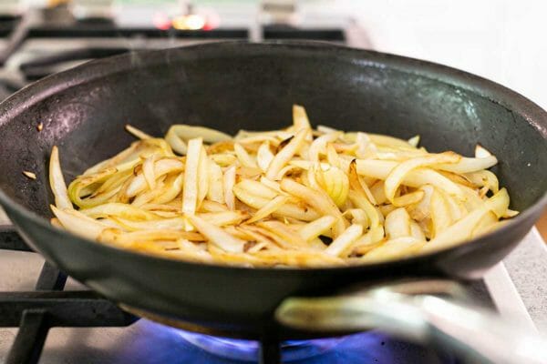 A melhor caçarola de frango e arroz da panela de barro acrescenta cebolas à frigideira de ferro fundido