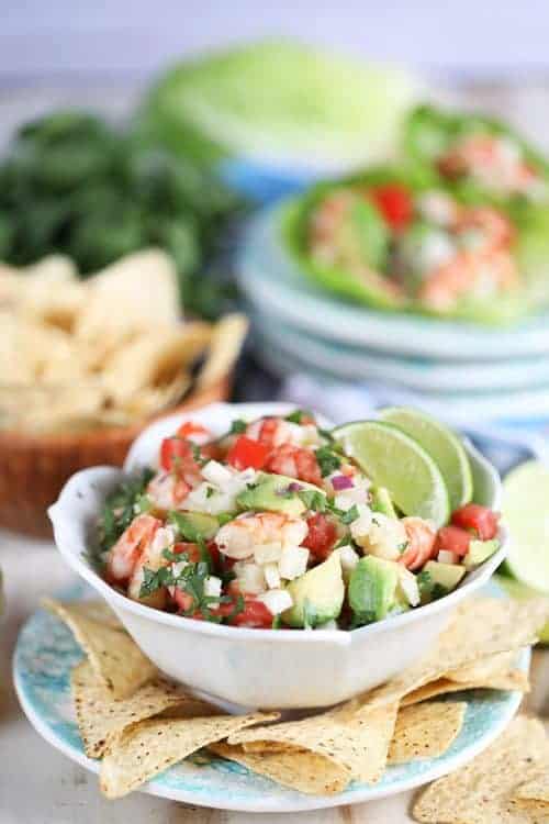 Ceviche de camarones en un tazón blanco con chips de tortilla y rodajas de lima de 