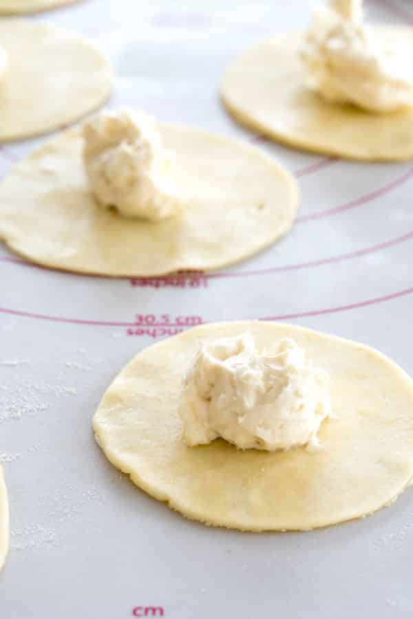 Preparação de cheesecakes com sopapilla: Mini rodelas de massa de bolo com uma colher de sopa de recheio de creme de queijo no centro