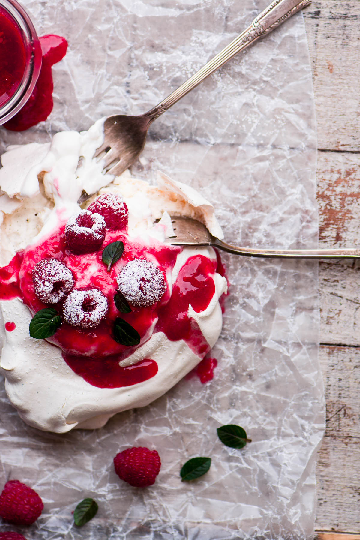Uma fotografia aérea de um único pavlova de framboesa com chantilly e framboesas.