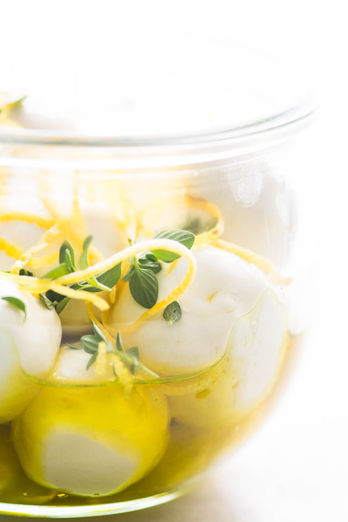 Como fazer queijo labneh ~ Bolas de queijo labneh em uma jarra de vidro com azeite, raspas de limão e folhas de tomilho fresco