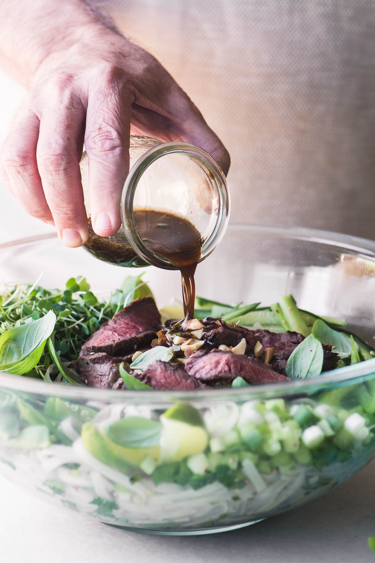 Adicione o molho à tigela grande de vidro da salada Thai Steak Pad