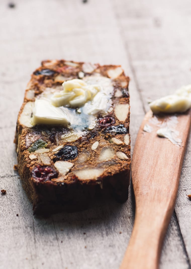 Uma fatia de Paleo Fruit and Nut Breakfast Bread com manteiga.