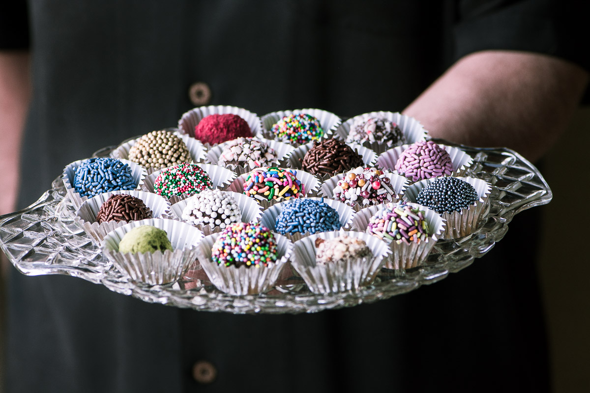Trufas de caixa de jóias ~ Eu desafio você a encontrar um alimento festivo mais fácil do que esses bombons deslumbrantes. Se você pode derreter o chocolate, você pode fazê-lo! #recipe #comida #ganache #christmas #comida # doces # chocolates #sprinkles #nobake #decoration #dessert Uma bandeja de vidro de trufas coloridas Jewel Box