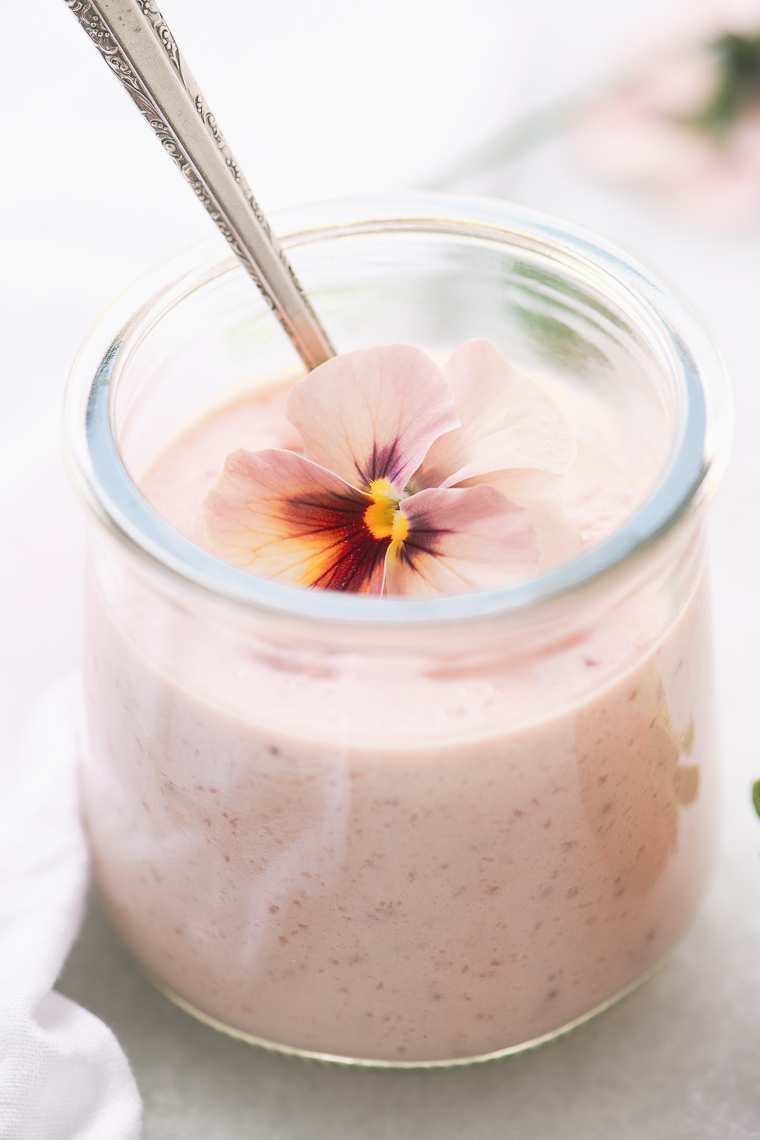 Morangos e creme em uma jarra de iogurte de vidro pequeno