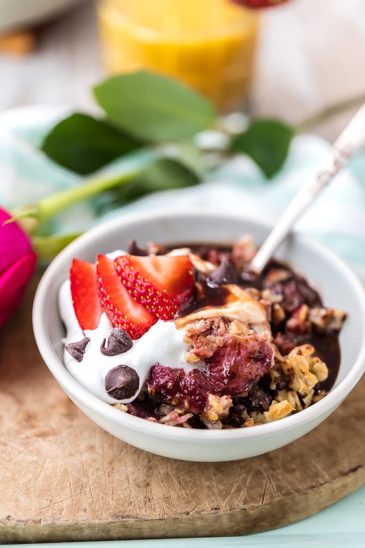 aveia de chocolate e morango em uma tigela branca, coberta com chantilly e morangos