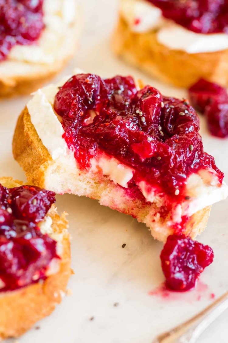 Uma fatia de crostini com queijo brie e molho agridoce de cranberry.