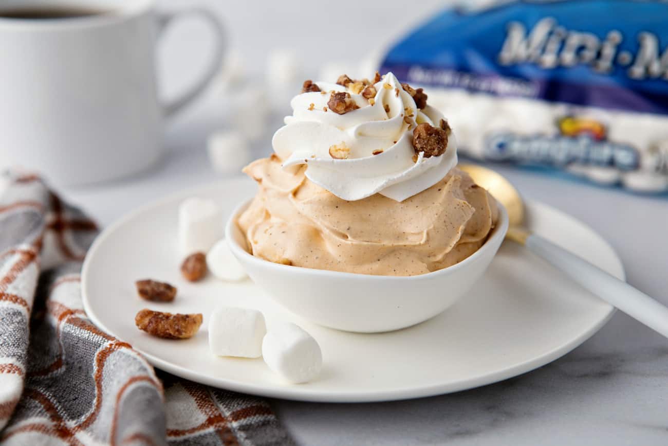 Tigela de penugem de especiarias de abóbora com uma xícara de café e um saco de mini marshmallows