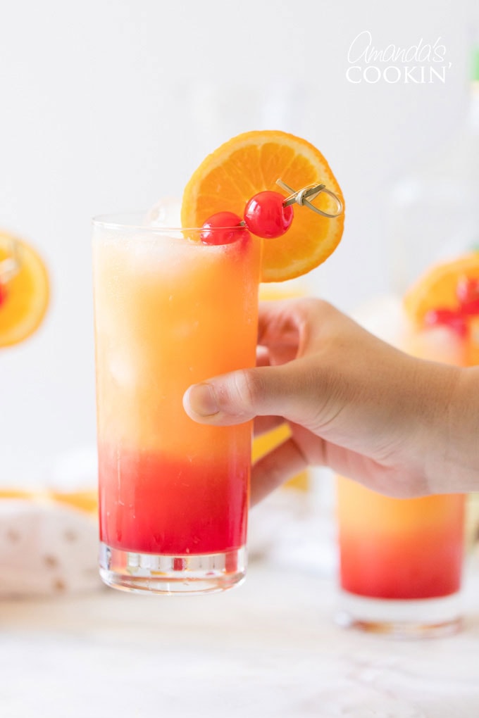 Mano sosteniendo tequila sunrise drink