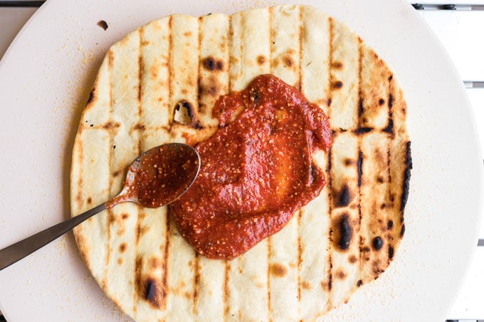 espalhe o molho sobre a massa de pizza na grelha
