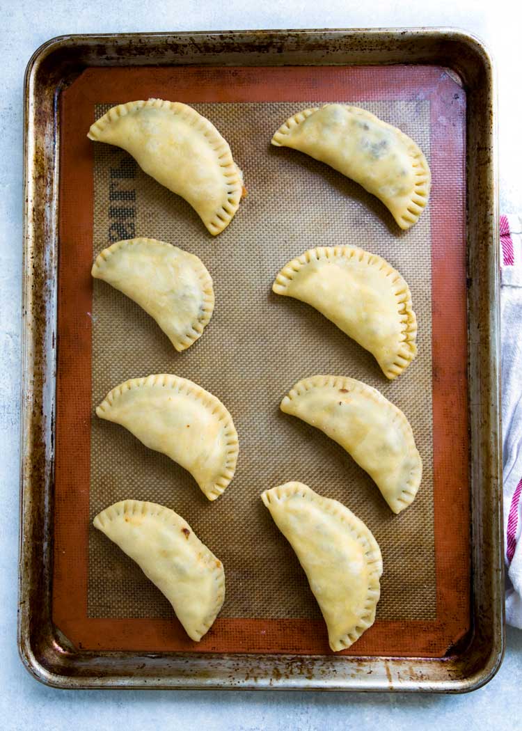 Empanadas Mendocinas são empanadas argentinas assadas recheadas com carne, cebola, temperos quentes, ovos cozidos e azeitonas. Receita de massa incluída! Keviniscooking.com