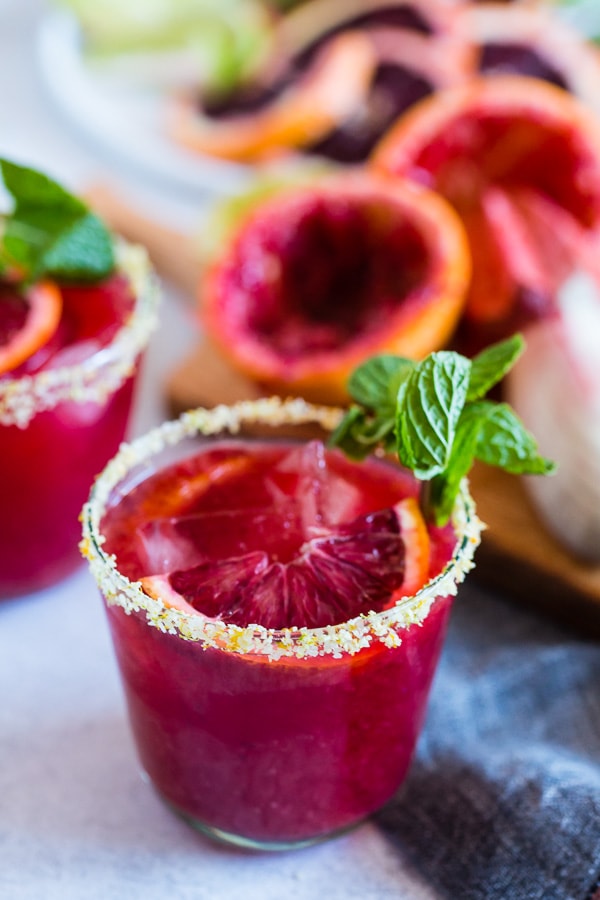 Esta margarita de laranja e gengibre é o coquetel perfeito para as suas festas de fim de semana! Este bebê usa laranjas sanguíneas e as combina com gengibre quente, suco de limão, tequila e xarope de agave. Você vai adorar o quão fácil é fazer esses coquetéis frescos e sazonais!