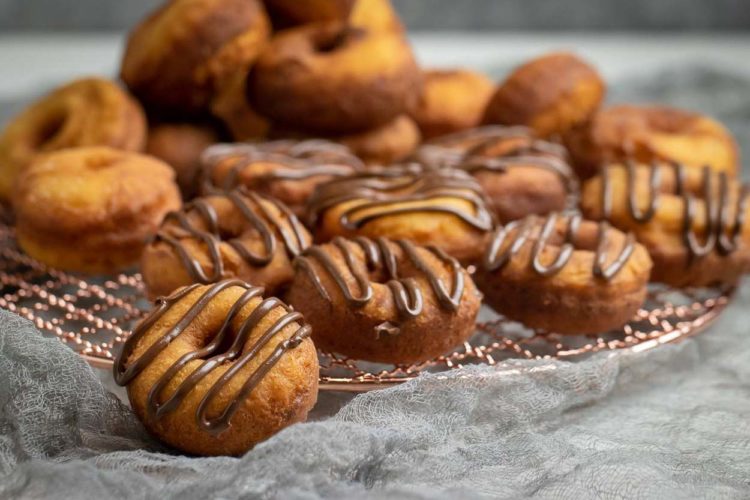 Uma receita incrível de mini rosquinha que é rápida e simples com queijo ricota. Estes donuts sem fermento são a sobremesa perfeita para qualquer ocasião! Rosquinhas caseiras em um rack de resfriamento regados com chocolate Nutella.
