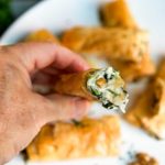 Frango, nozes e recheio de queijo de espinafre, todos embrulhados em camadas de massa de panqueca escamosa, tornam esses rolos de frango Spanakopita com nozes tão irresistíveis. keviniscooking.com