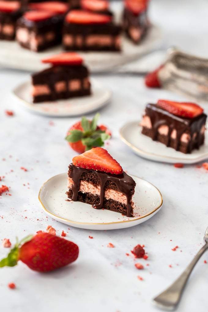 Pastelitos de chocolate sentados en mini platos blancos con fresas rodeándolos