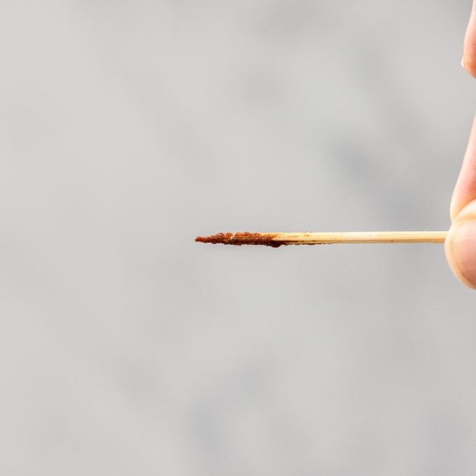 Um palito mostrando massa de brownie mal cozida