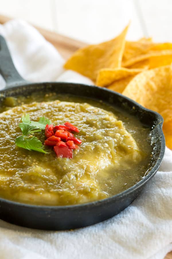 Mergulho De Queijo Fresco Cozido No Molho Verde Verde. Sirva este aperitivo em uma frigideira de ferro fundido com batatas fritas!