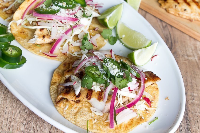 Tacos de peixe grelhado marinados em cerveja, esses tacos clássicos são cobertos com repolho ralado, rabanetes, cebola roxa em conserva, fatias de jalapeño e queijo cojita.