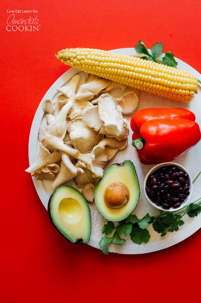 Aguacate, frijoles negros, champiñones ostras, maíz y pimiento rojo en un plato para panecillos de verano al estilo mexicano