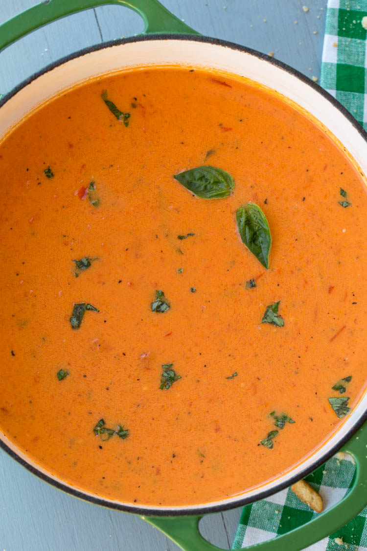 Sopa cremosa de manjericão e tomate em forno holandês coberto com manjericão fresco. 
