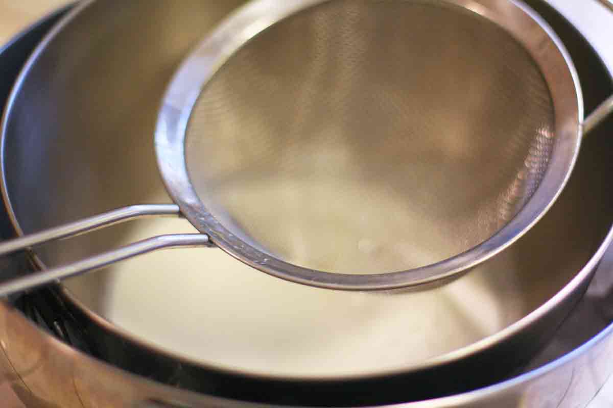 filtro de malha sobre a tigela de creme de gemada