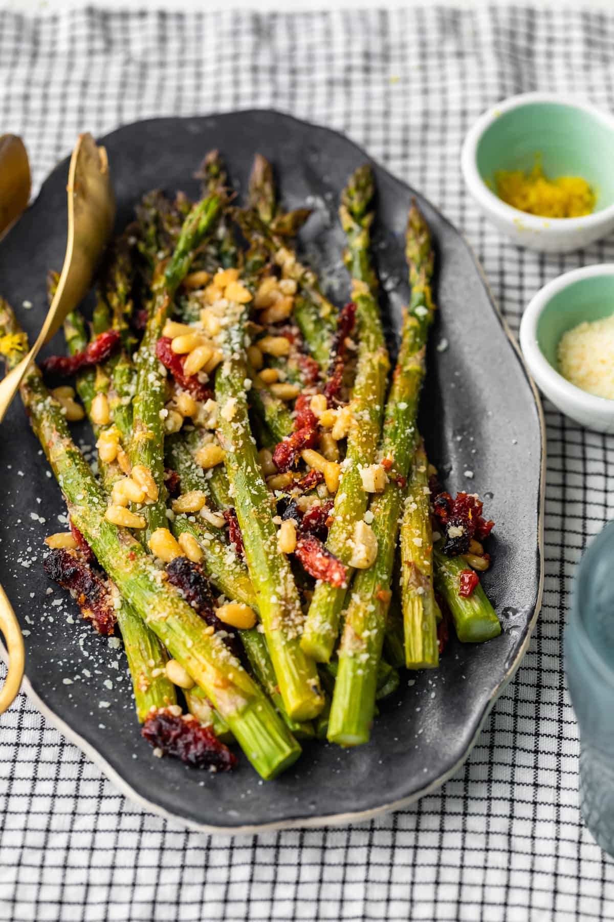 un plato de espárragos mezclado con tomates secados al sol, piñones y más