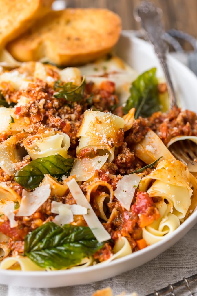 Salsa boloñesa mezclada con pasta, queso fresco rallado y albahaca