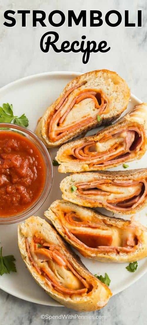 Rebanadas de esta sencilla receta de Stromboli sentada en un plato blanco y rodeando un tazón claro de salsa