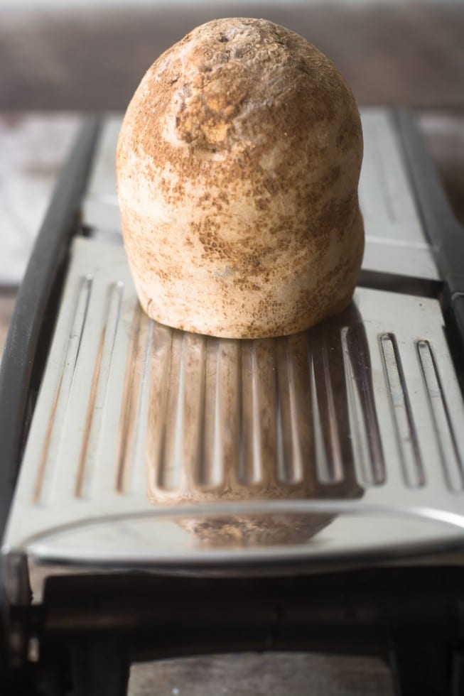 Fatiar batatas em um bandolim para batatas fritas finas