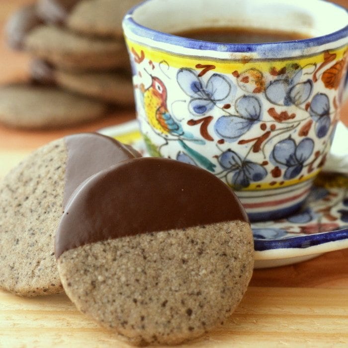 Foto de galletas de mantequilla de caf&eacute; turco ba&ntilde;adas en chocolate junto a una taza de caf&eacute; en un platillo.