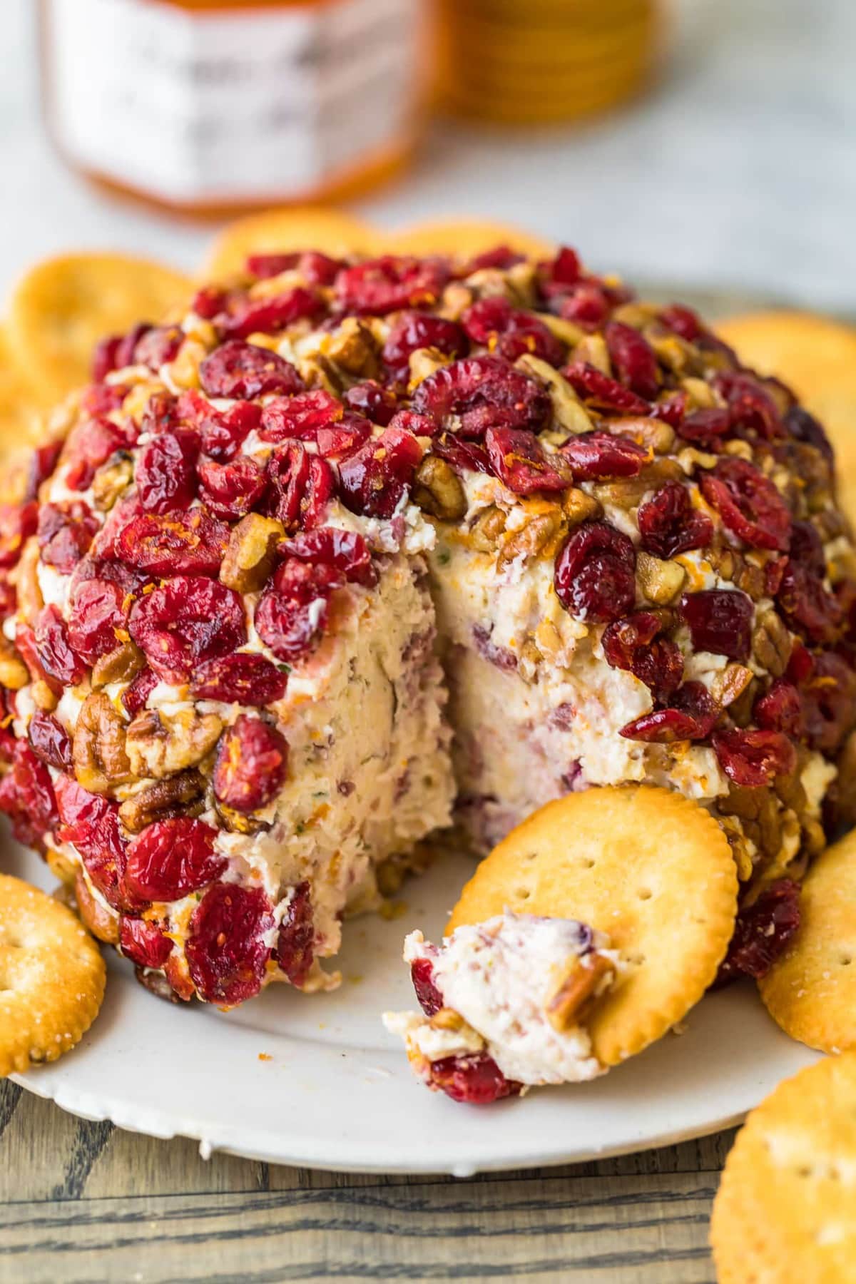 Una bola de queso de navidad con ar&aacute;ndanos y una naranja en un plato para servir