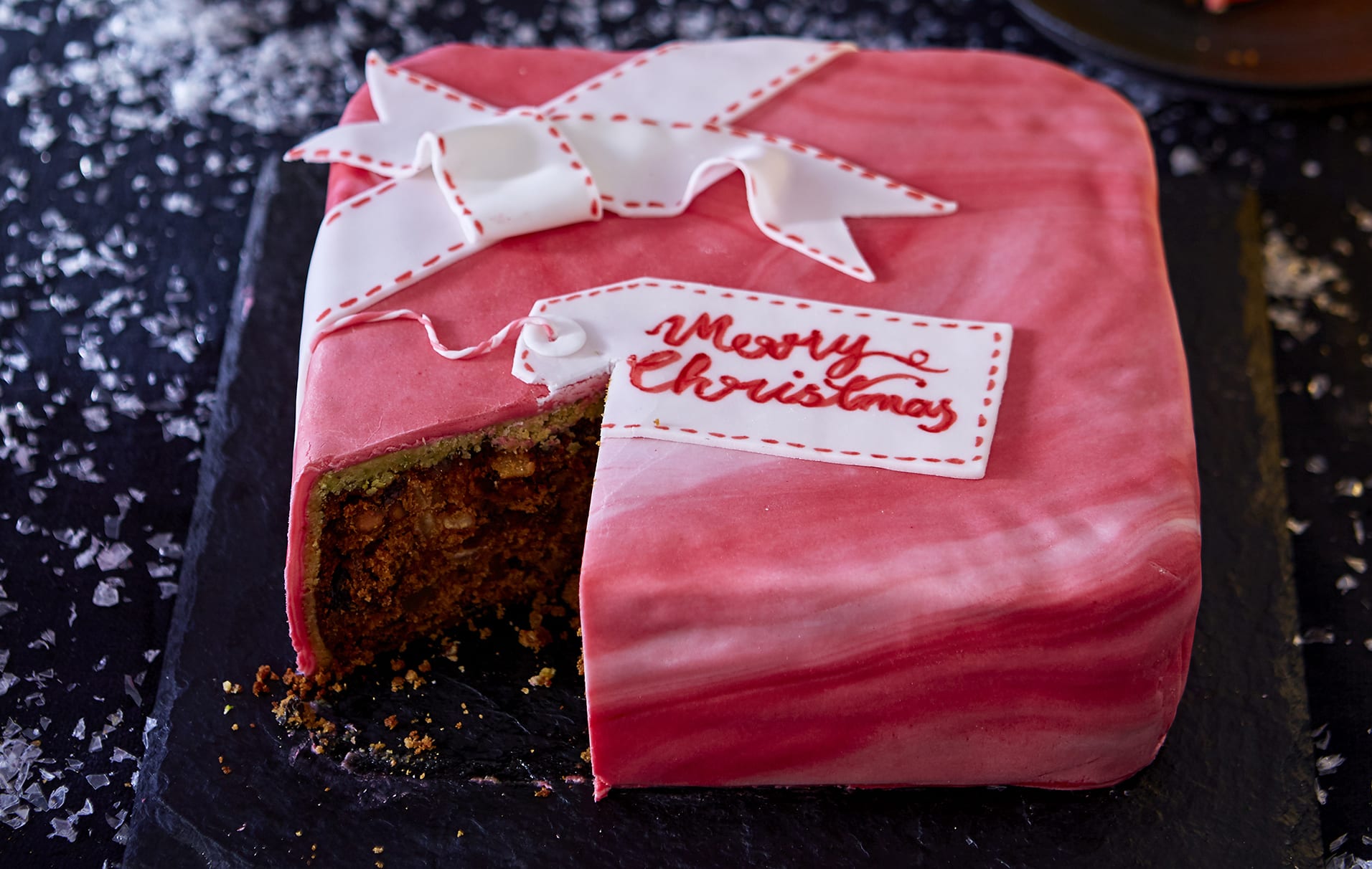 Bolo de presente de Natal Este magnífico bolo de Natal é um verdadeiro espetáculo, aromatizado com pistache, clementina, muitas nozes e uma pitada de rum.