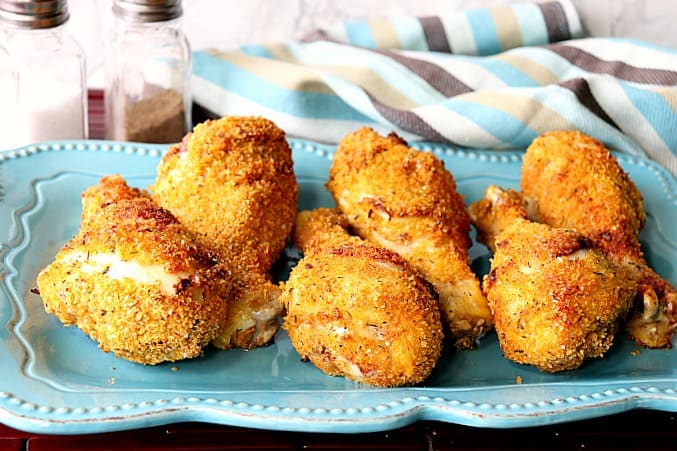 Six chicken drumsticks sitting on a blue plate with a napkin.