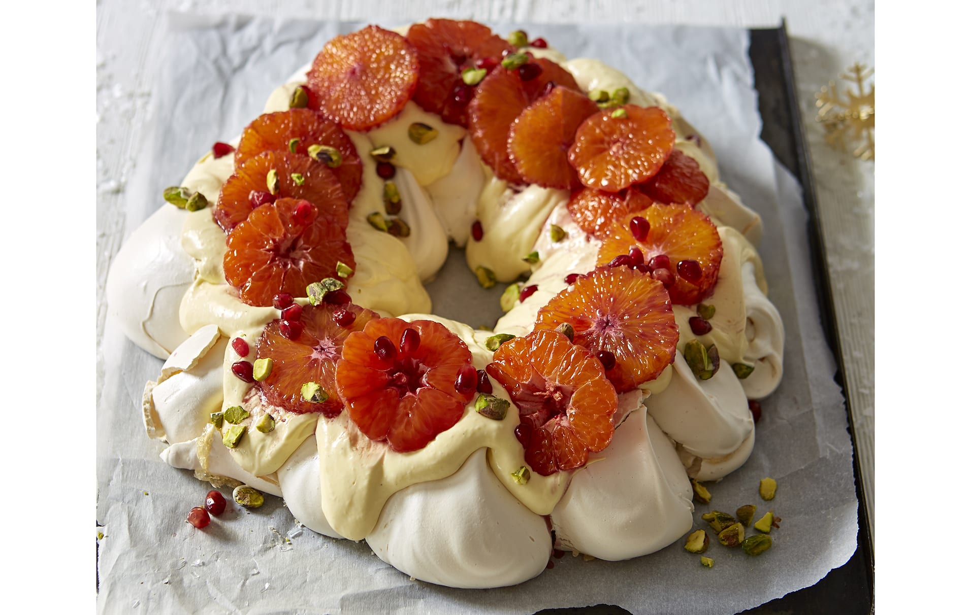 Guirlanda de Natal Pavlova com vinho quente Este pavlova clássico de Natal é coberto com fatias de laranja embebidas em vinho quente, pistache e sementes de romã, e certamente adicionará um toque de brilho a qualquer celebração festiva.