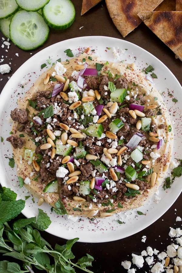 Este hummus griego cubierto est&aacute; lleno de sabor. Cubierto con cordero especiado, pepino, cebolla roja, pi&ntilde;ones, queso feta, menta y una pizca de zumaque. &iexcl;Sirve con chips de pita y DIG IN!