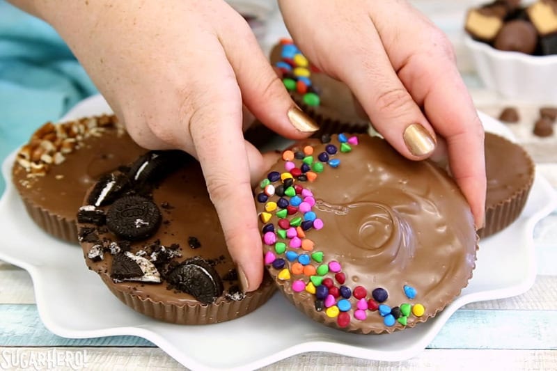Mega tazas rellenas de mantequilla de man&iacute;: manos que sostienen una taza gigante de mantequilla de man&iacute; con chips de arco&iacute;ris